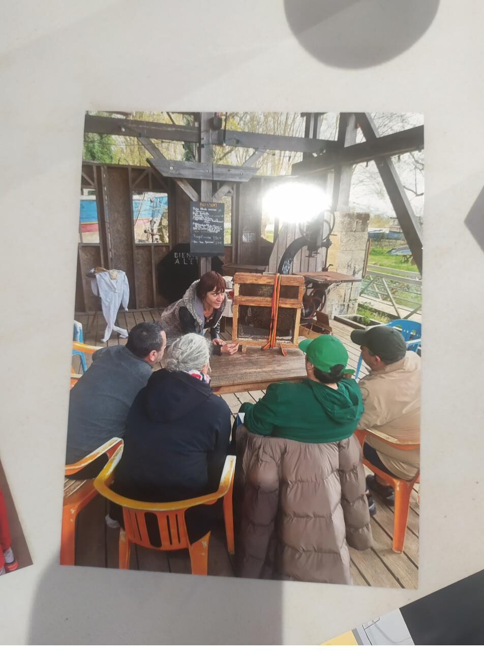 Tirage exposé montrant un groupe réuni autour d'une table sous un abri en bois