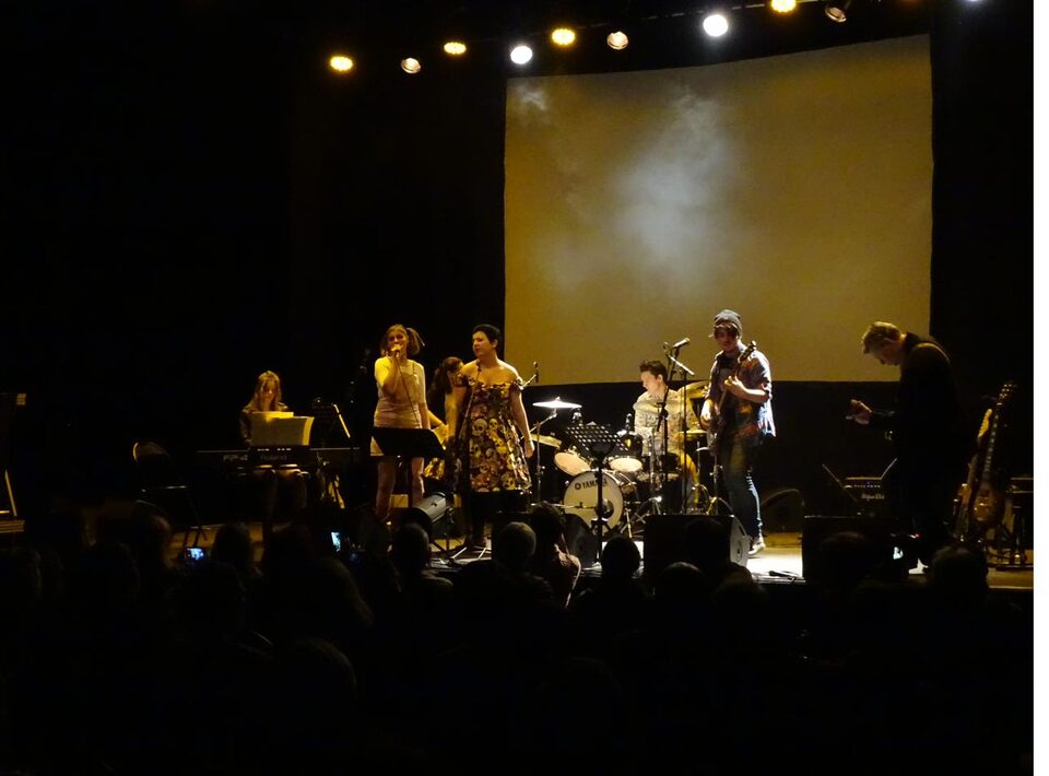 Groupe de musiciens sur scène devant un écran de projection