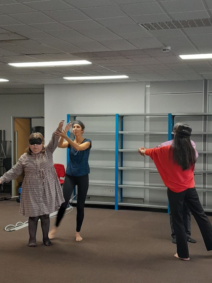 Atelier de danse dans une salle claire, trois participantes en mouvement, dont une aux yeux bandés
