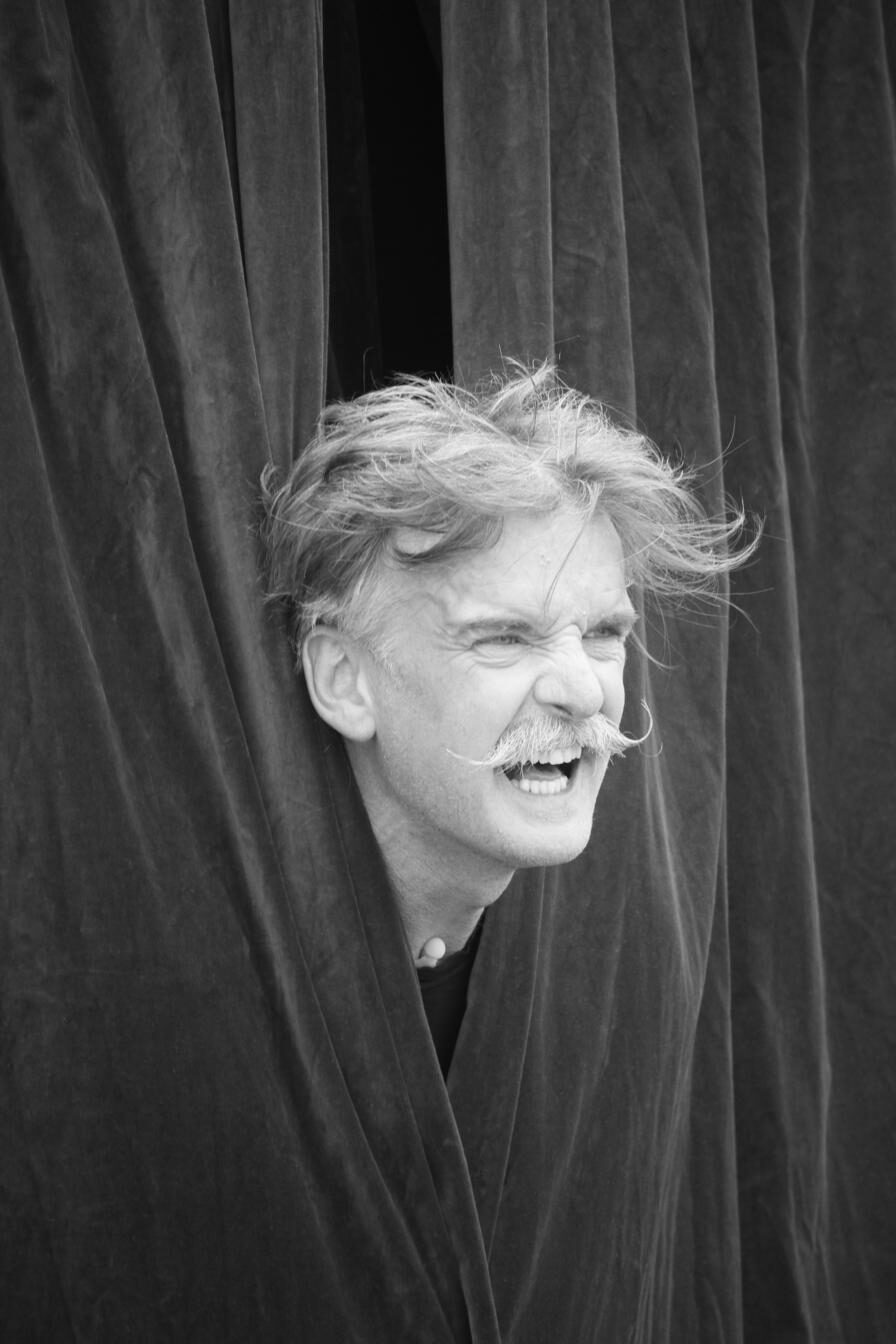 Portrait d'un artiste souriant entre les rideaux de scène, noir et blanc