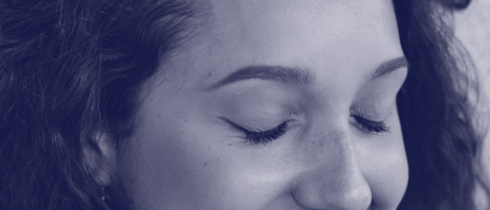 Gros plan en bleu sur le visage d'une femme qui sourit, les yeux fermés.